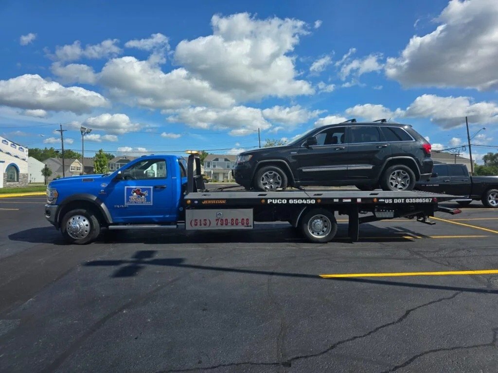 Camión grúa remolcando SUV negro